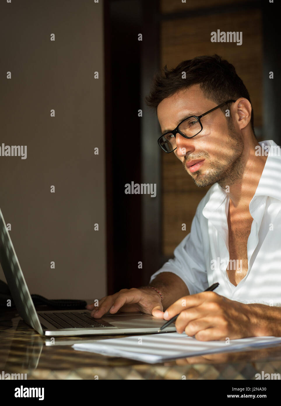 Good-look men sitting front laptop and thinking with shadows of daylights Stock Photo