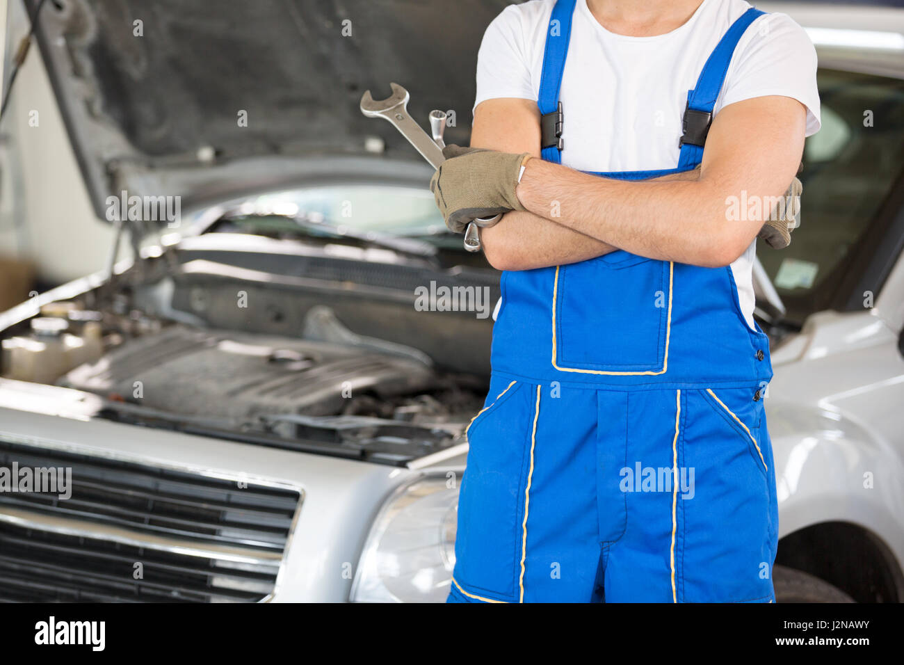 Mechanic with the tools next to an open hood Stock Photo