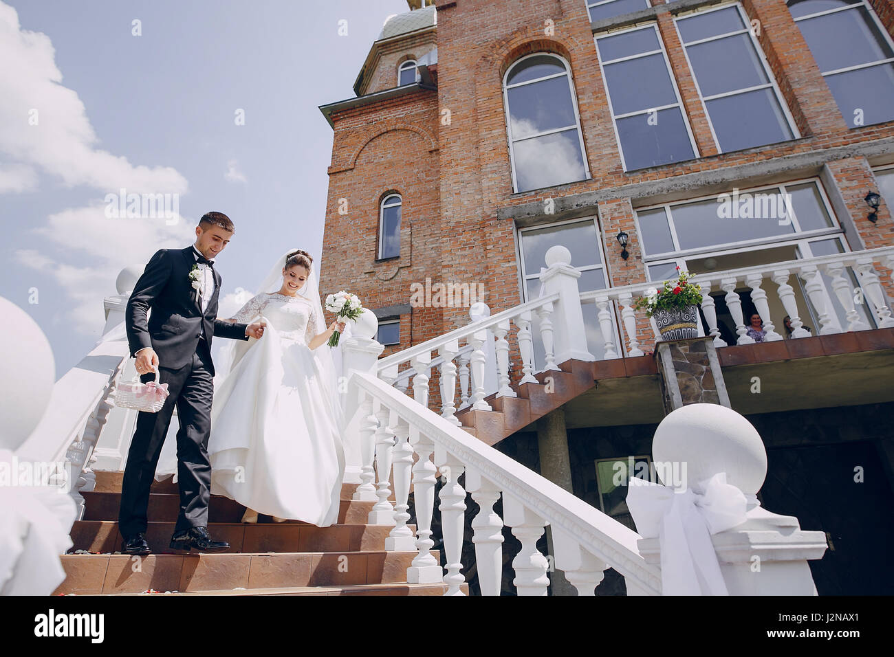 the bride and groom stand near the big house and windows Stock Photo ...