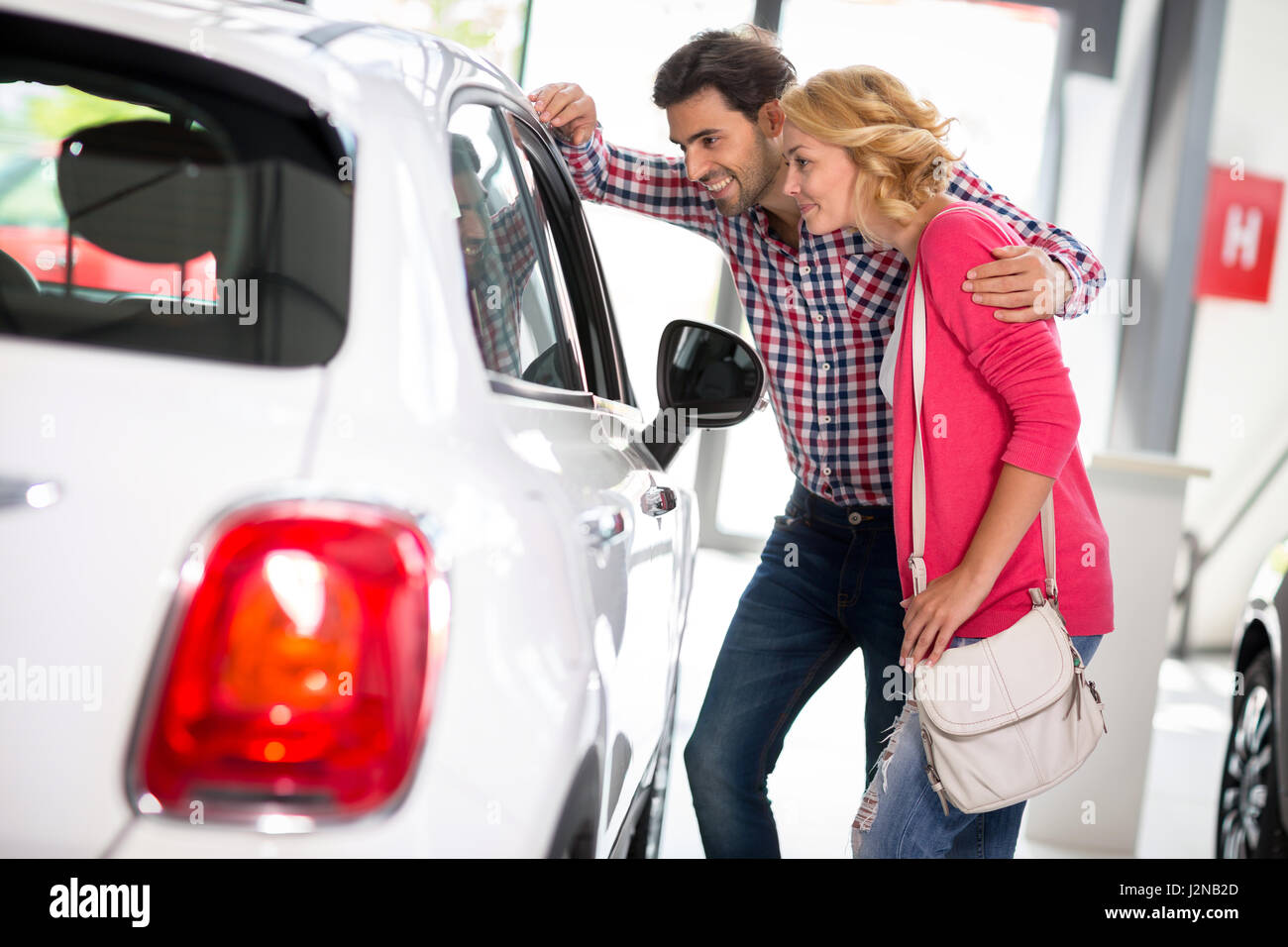 Young  couple chooses to buy a car in car dealership saloon Stock Photo