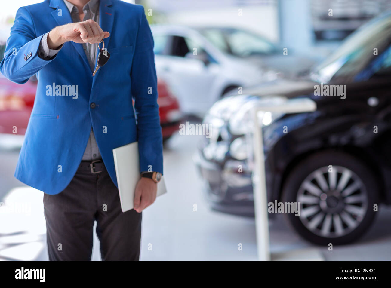 car agent  in car dealership saloon holding car key in front of him Stock Photo