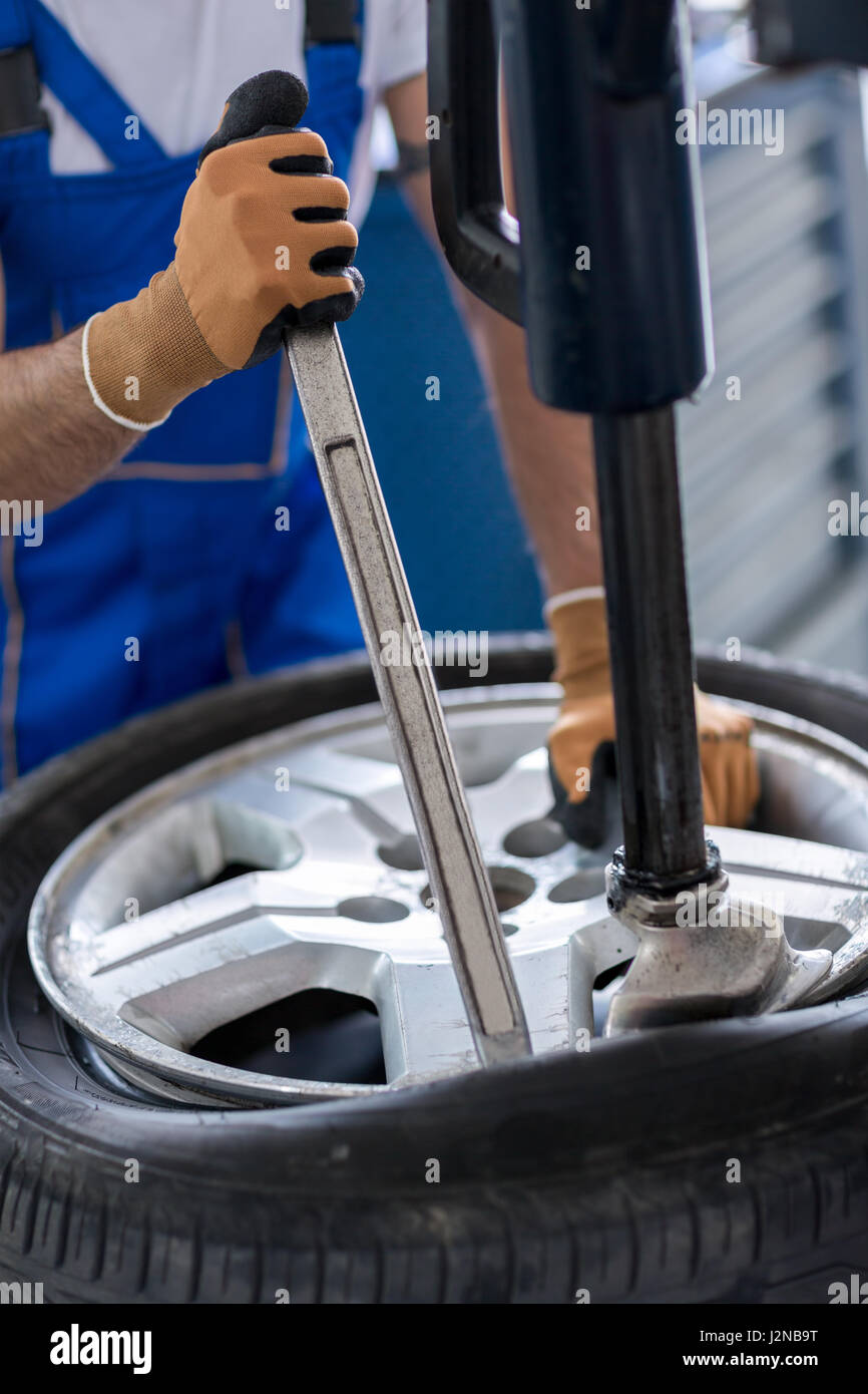repairman with installer replace tire on wheel in Stock Photo