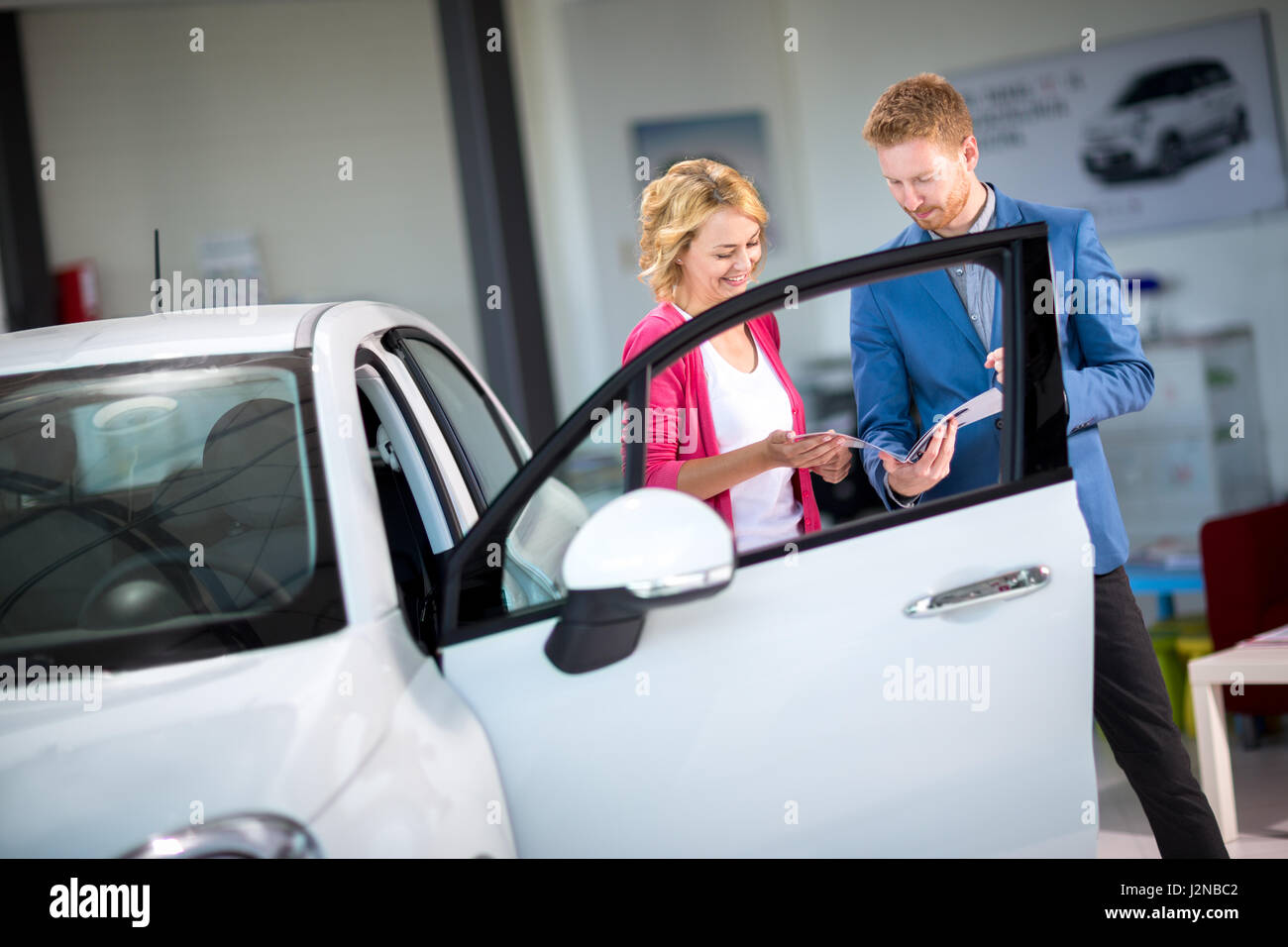 Young woman looking at brochure with salesman in car showroom Stock Photo