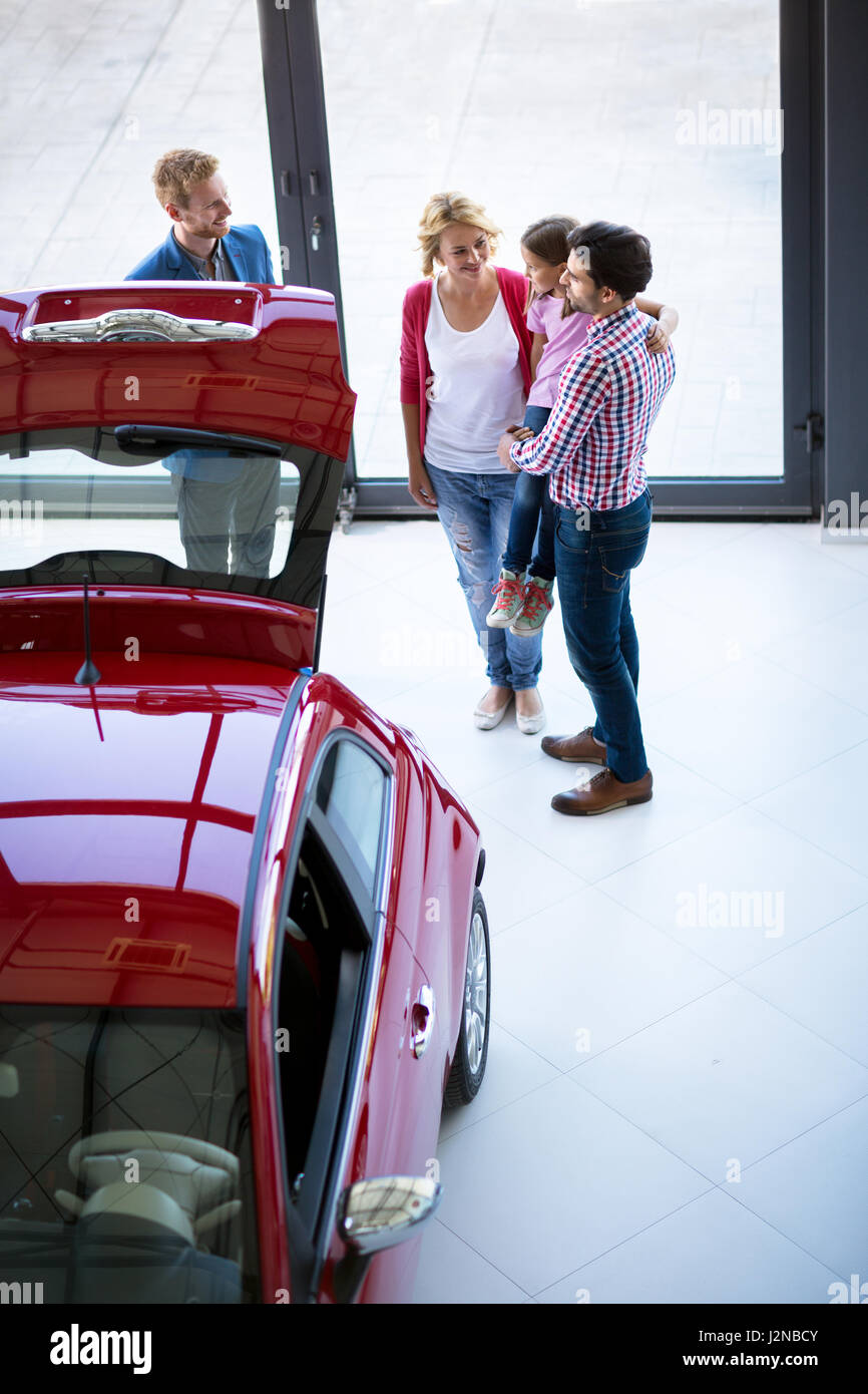 Salesman offering a car to family in the car dealership  saloon, overhead view Stock Photo