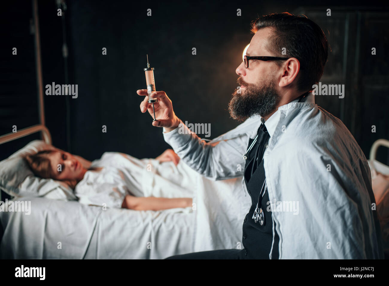 Male doctor with syringe against sick woman in hospital bed. Illness of female patient in clinic, health recovery and treatment Stock Photo