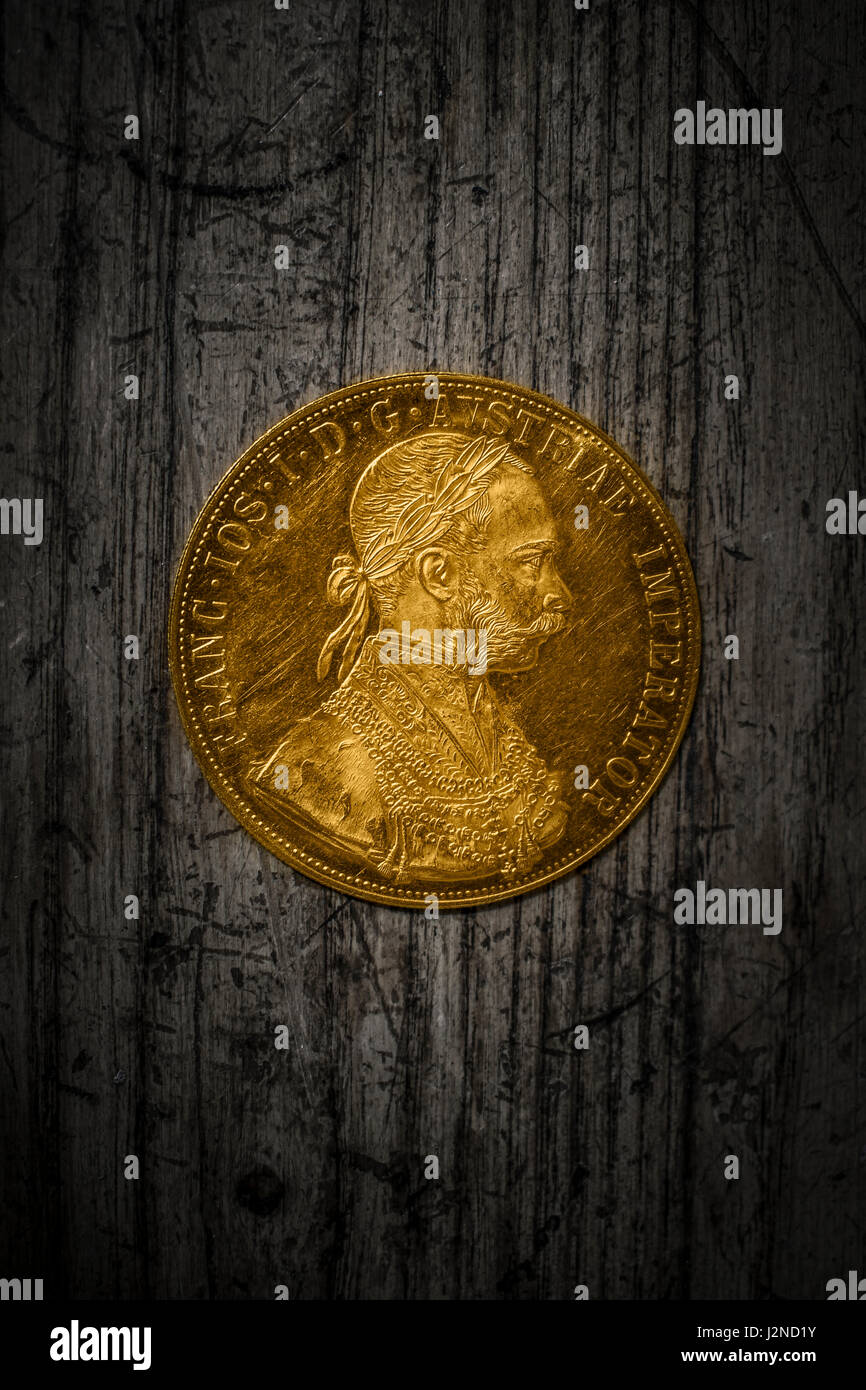 Close-up view of Austria-Hungary thaler, avers of golden coin-ducat from 1915 with Kaiser Franz Joseph I on dark wooden background Stock Photo