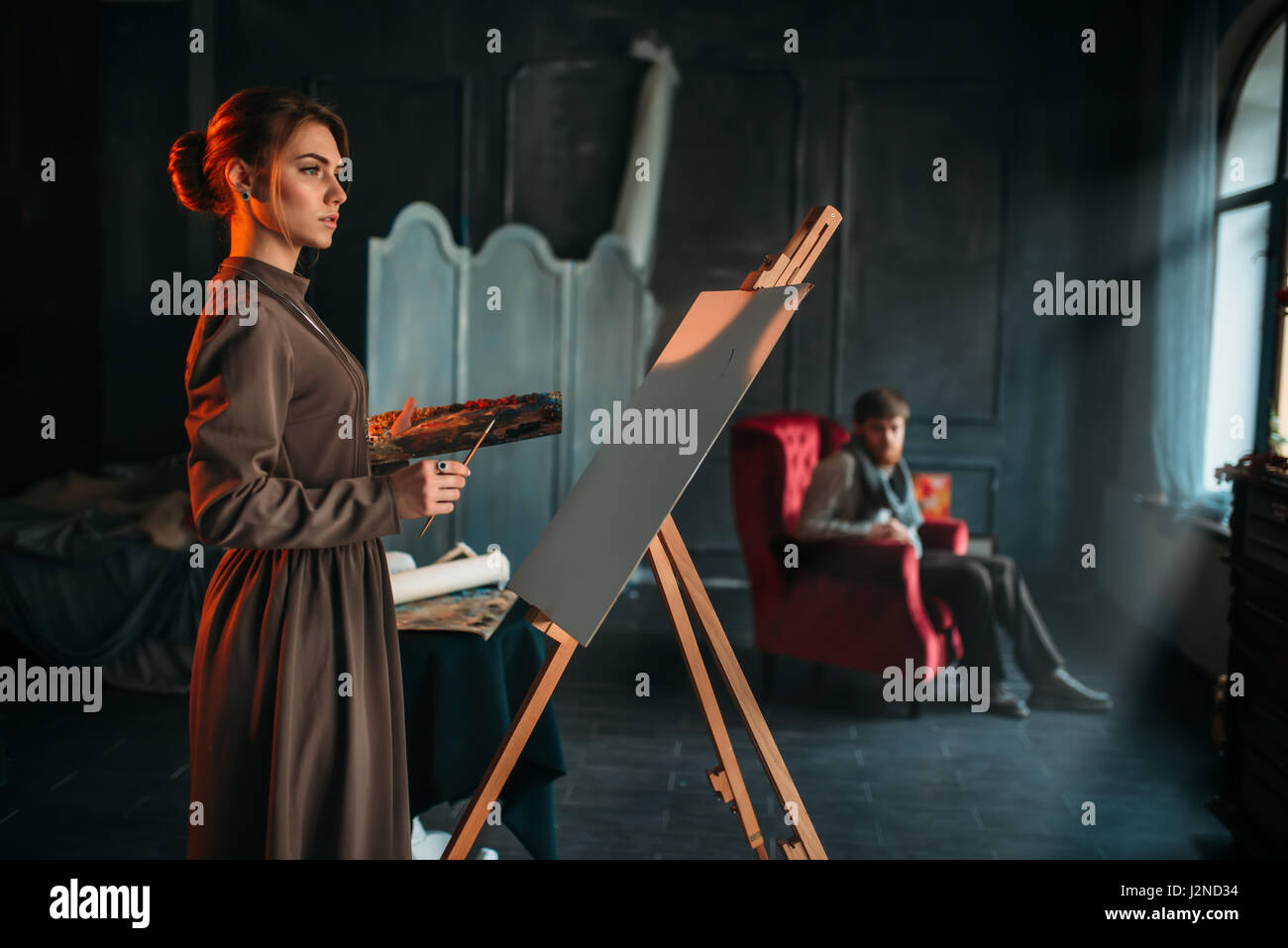 Female painter with brush and palette in hands in art studio. Oil paint ...
