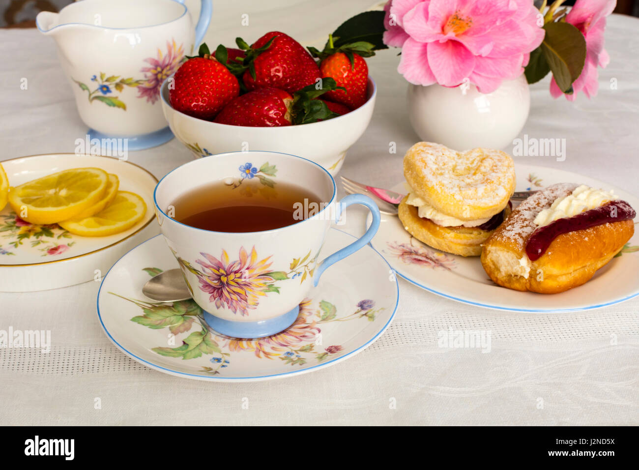 Cup of tea served in a vintage fine china tea cup with cream cakes