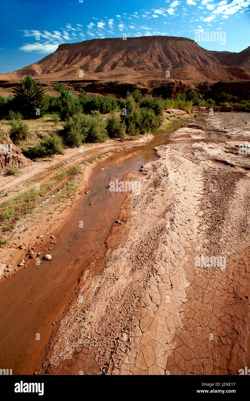 A parched river valley surrounded by the arid desert landscape of the Atlas Mountains in Morocco near the world heritage site of Ait Benhaddou. Stock Photo