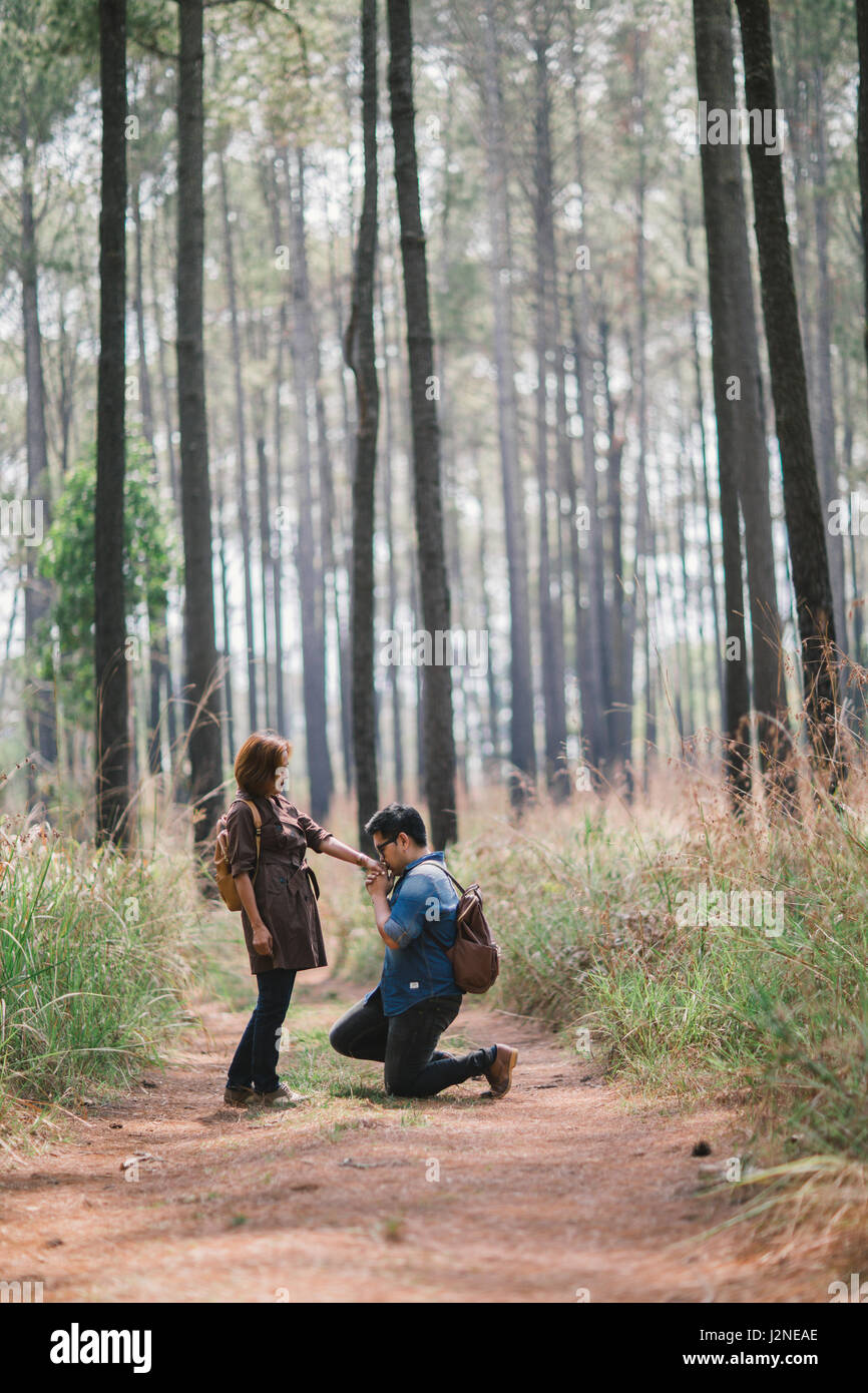 An Asian man make a romance down on one knee proposal in the pine forest, Thailand. Stock Photo