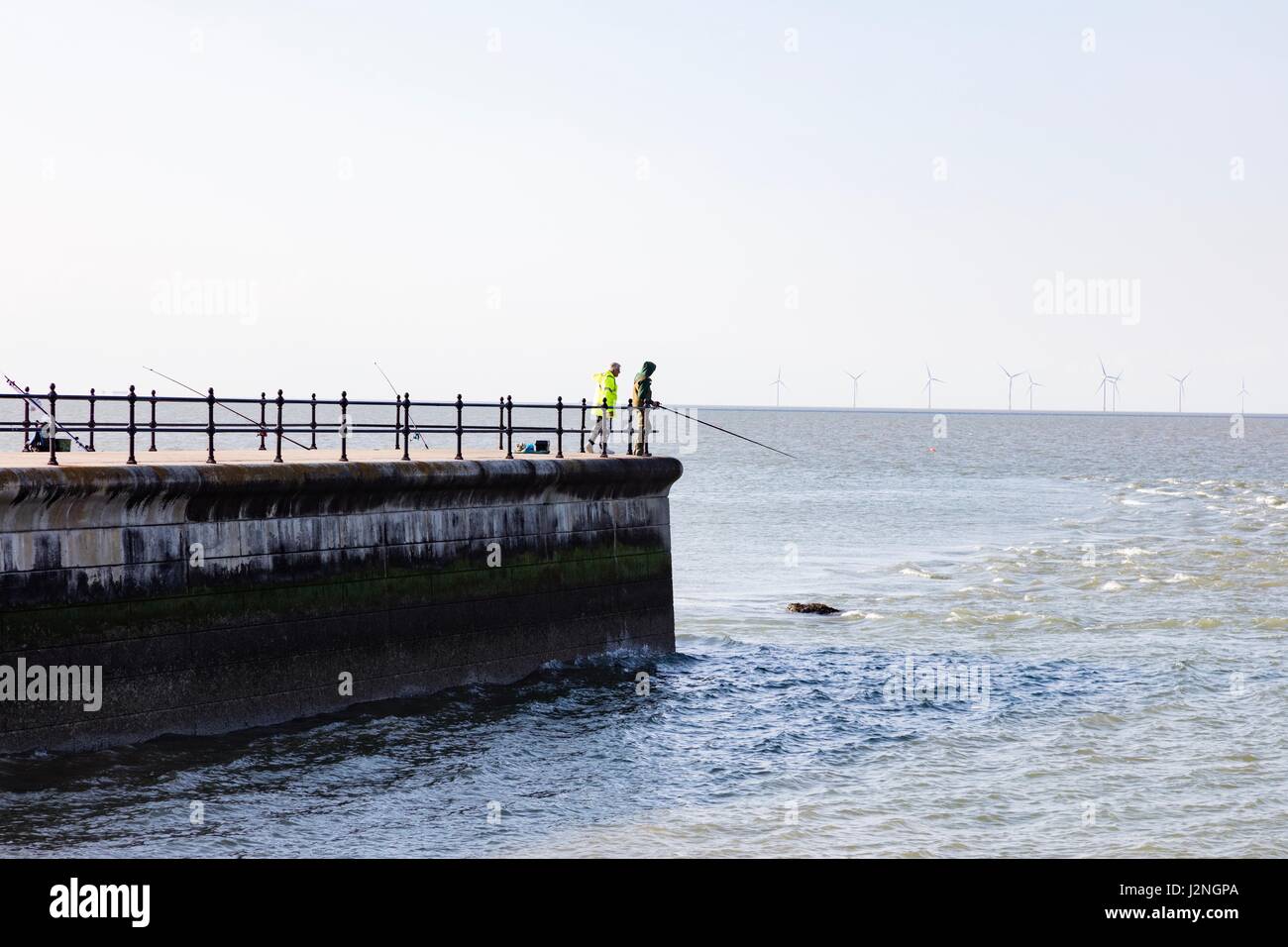 Herne Bay, Kent, UK. 29th April, 2017. UK Weather News.  A sunny evening on the first day of Mayday Bank Holiday weekend enables people to go to the beach although they remain wrapped up against the cold.  Two anglers fish off the pier at Hampton. Credit: Richard Donovan/Live Alamy News Stock Photo