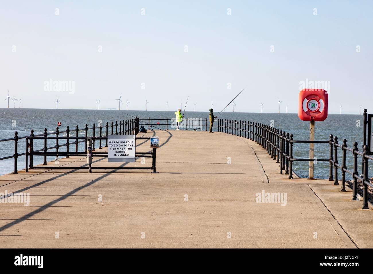 Herne Bay, Kent, UK. 29th April, 2017. UK Weather News.  A sunny evening on the first day of Mayday Bank Holiday weekend enables people to go to the beach although they remain wrapped up against the cold. Two anglers fish off the pier at Hampton. Credit: Richard Donovan/Live Alamy News Stock Photo