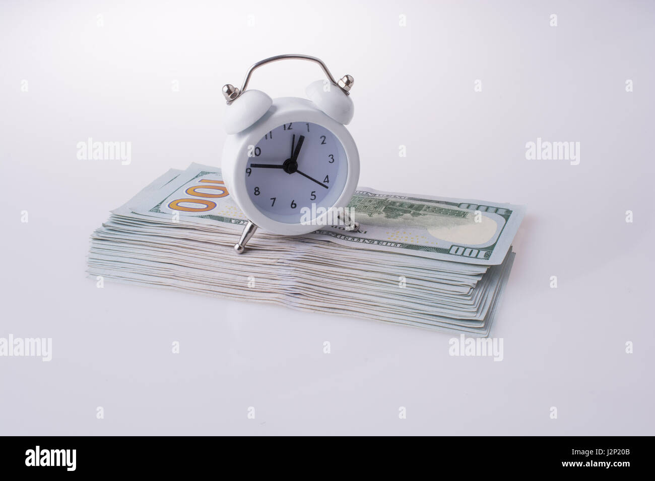 American dollar banknotes by the side of a alarm clock on white