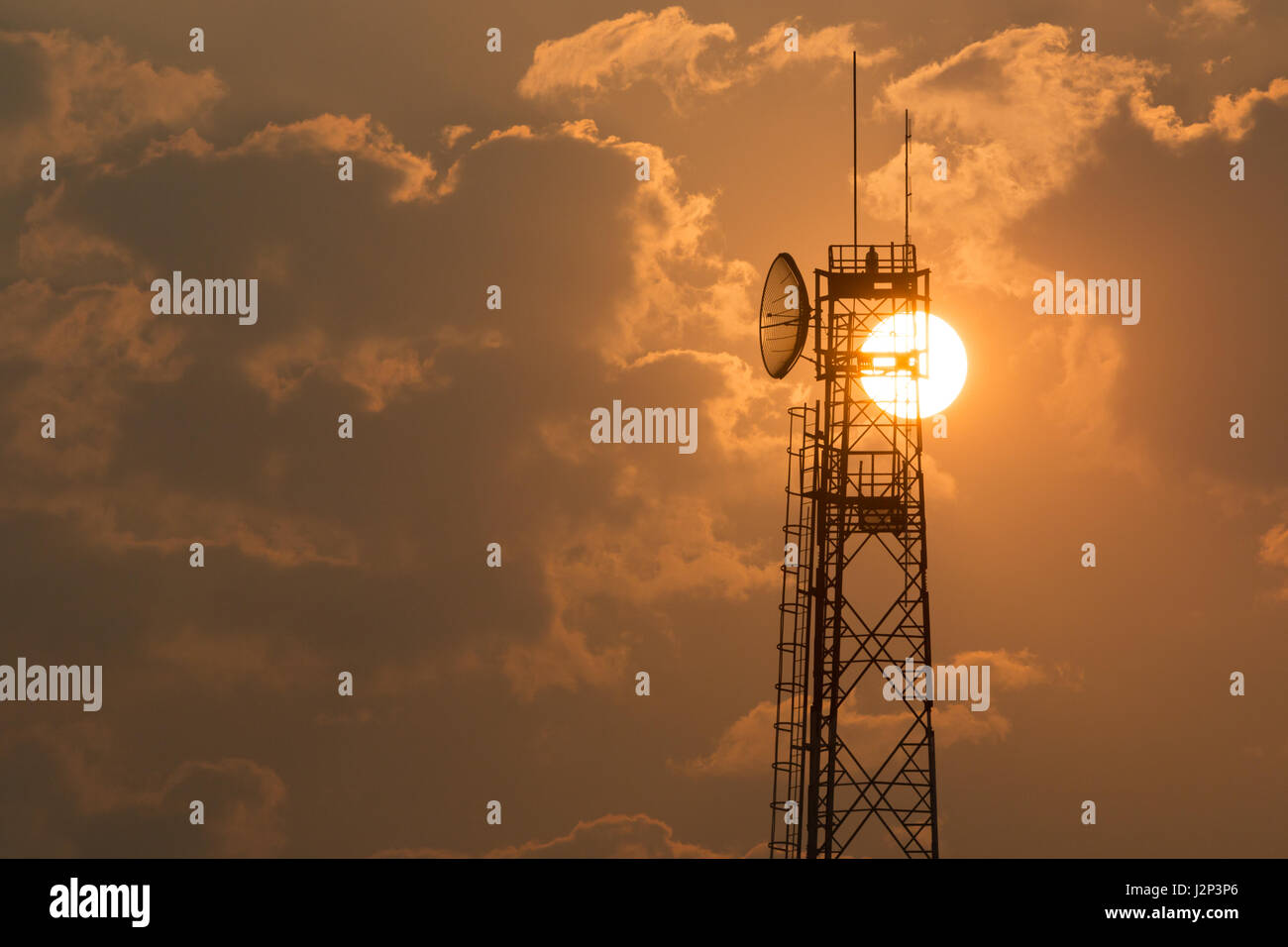 Communication tower at sunrise against sunrise with clouds Stock Photo