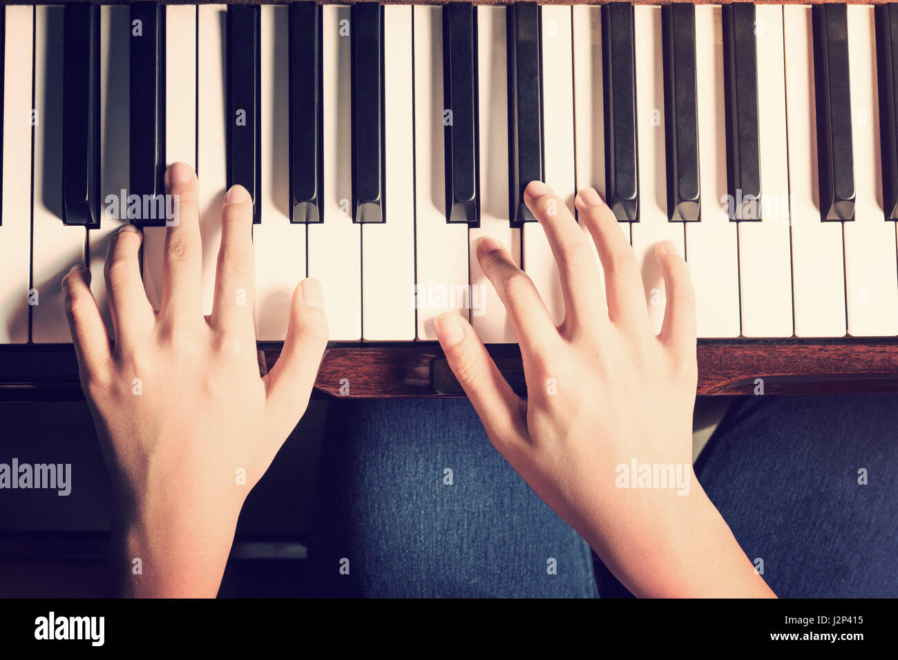 Female hands playing piano with high contrast vintage and retro look added Stock Photo