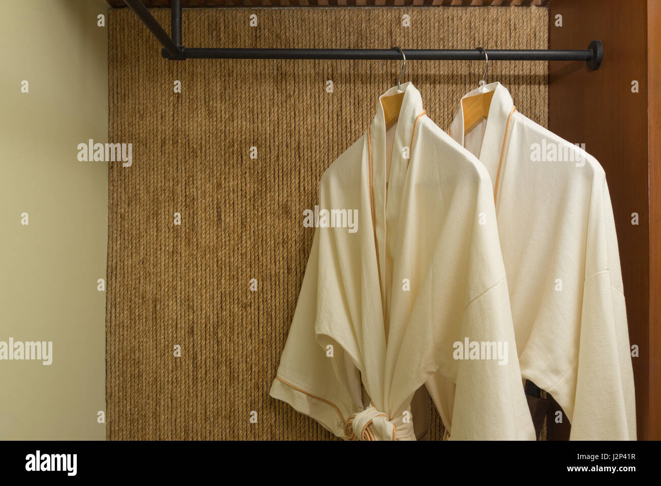 two off white color bathrobes hanging in warmly design closet, room for