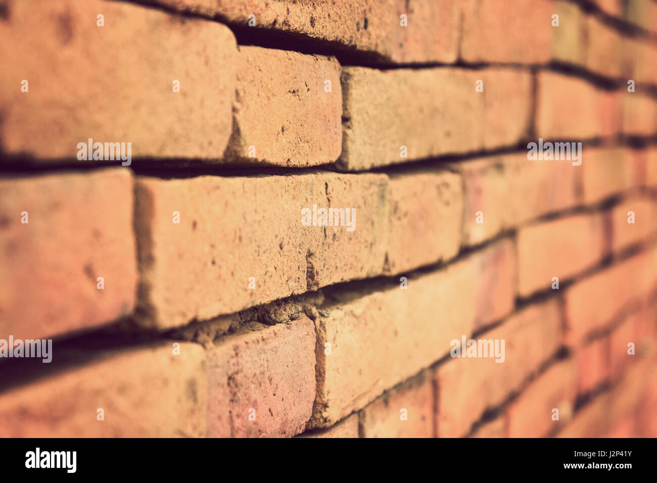 Terracotta brick wall shown in one point perspective with selective focus and shallow depth of field, in vintage retro color style Stock Photo