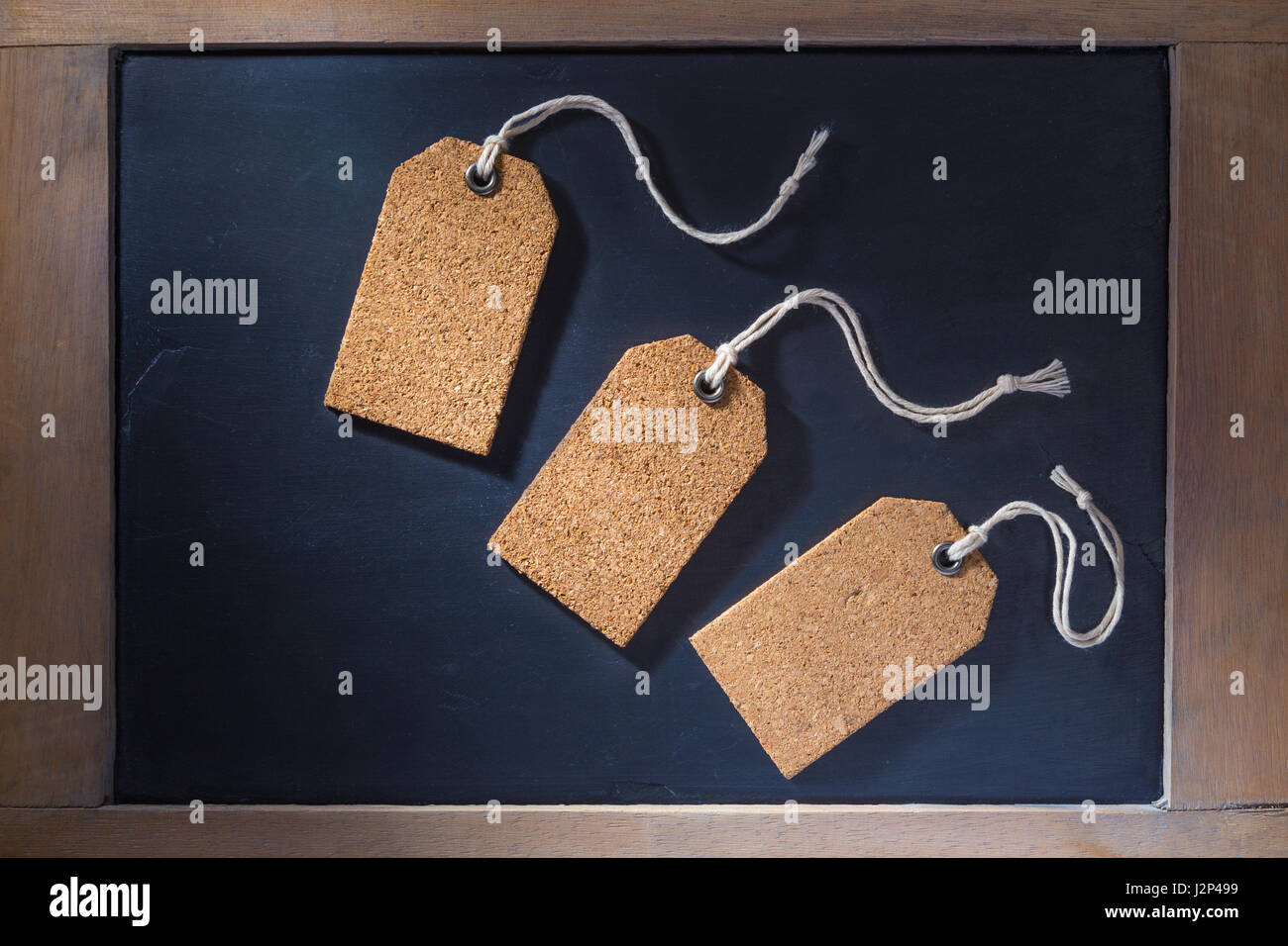 Empty cork tags on small chalkboard with wooden frame, hard lighting with hard shadows Stock Photo