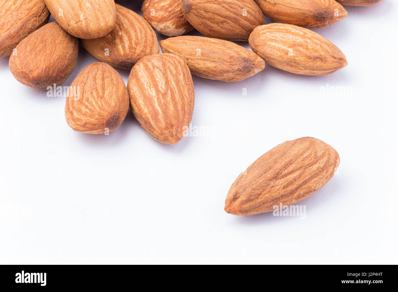 Close up of almonds on white in one seed separated from the pile Stock Photo