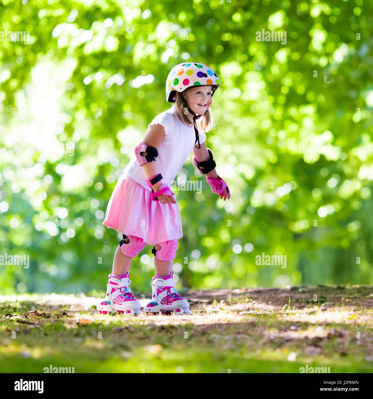 Little girl learning to roller skate in sunny summer park. Child