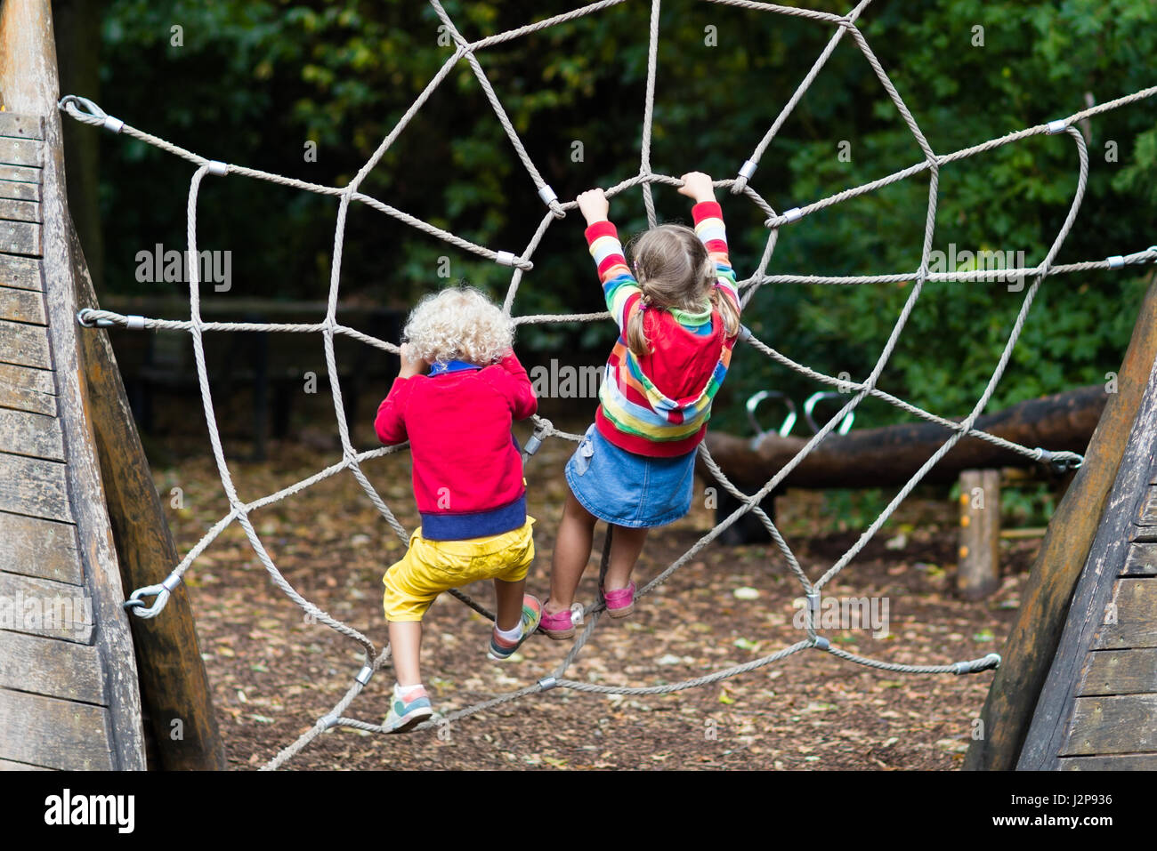 Active children playing on climbing net at school yard playground. Kids