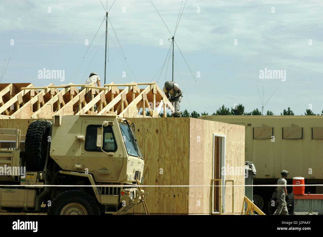 Soldiers with an Army engineer unit work on placing rafters on a small ...