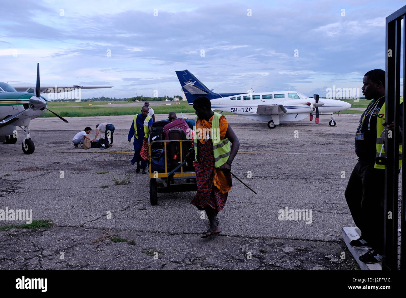Baggage handlers push luggage that has been unloaded from a small aircraft at Julius nyerere airport in Dar es Salaam, the largest city of Tanzania in eastern Africa Stock Photo