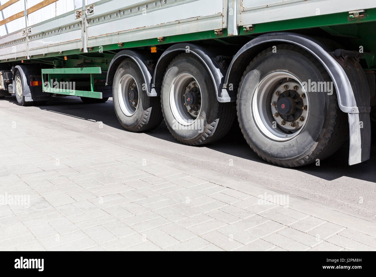 wheels of heavy truck with trailer on gray asphalt road. wide angle view. Stock Photo