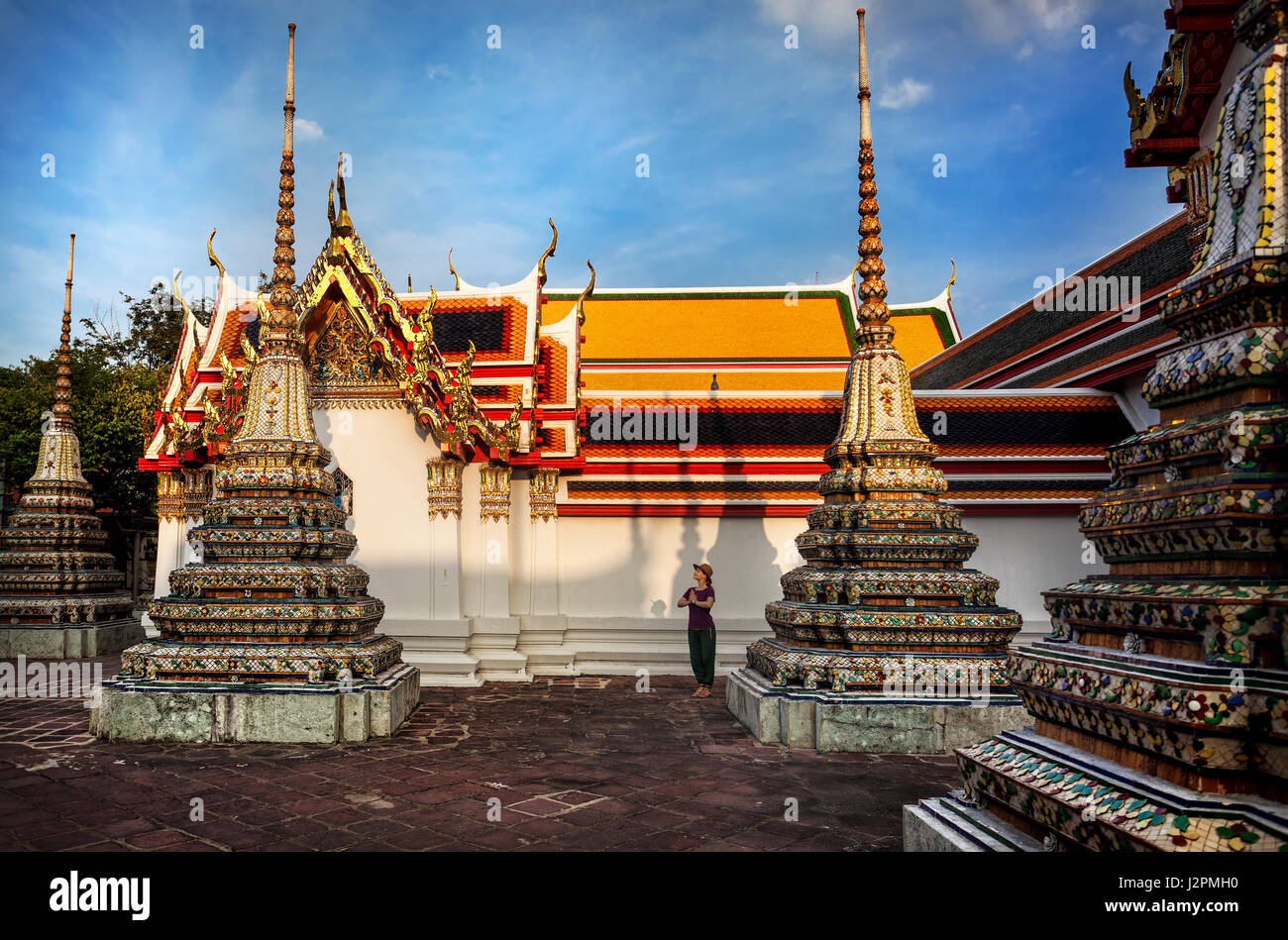 Woman tourist near Ancient Royal Stupas and pagoda in Wat Pho temple in Bangkok at sunset Stock Photo