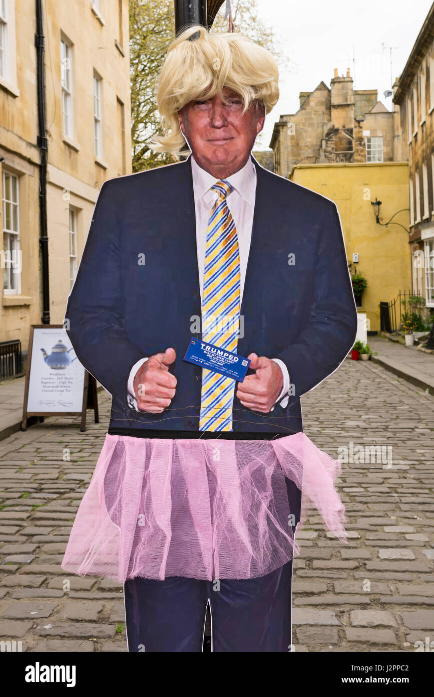 Real size copy of Donald Trump, current US president, in cardboard dressed up with a pink skirt and a blonde wig attached to a street lamp in a street Stock Photo
