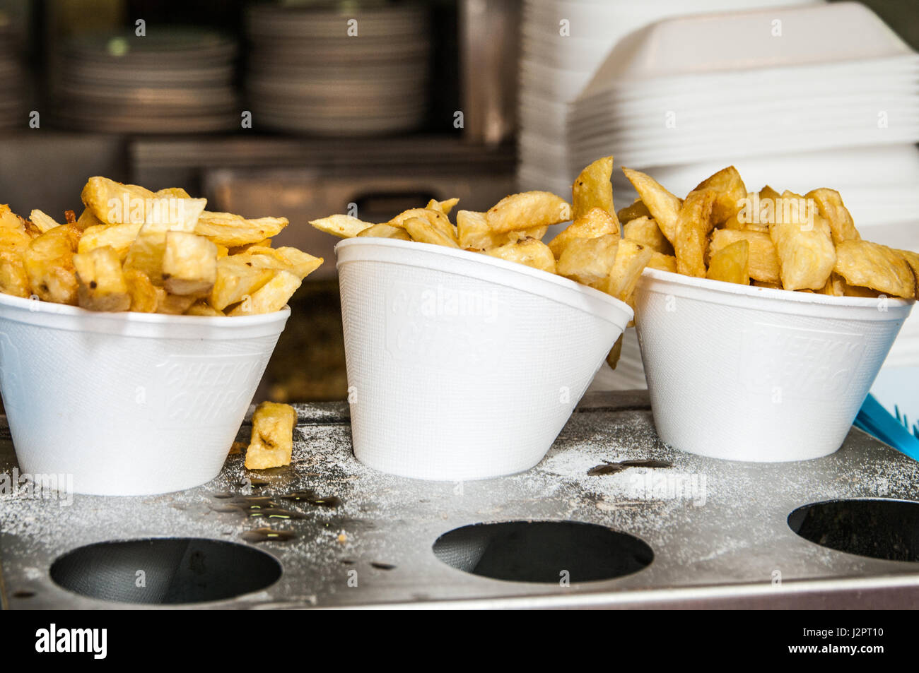 Fried potato chips in polystyrene cones in a fish and chip shop Stock