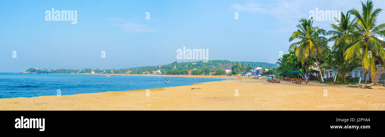 Panorama of Unawatuna beach with row of hotels and beach cafes, offering snacks and fresh beverages, Sri Lanka. Stock Photo