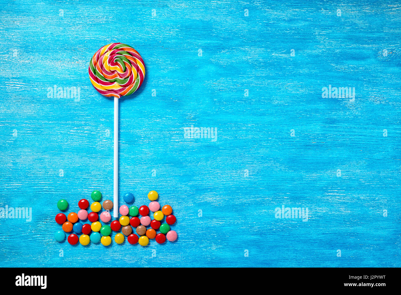 flat lay of beautiful multicolored lollipop and sweet bonbons on painted blue wooden background, close up Stock Photo