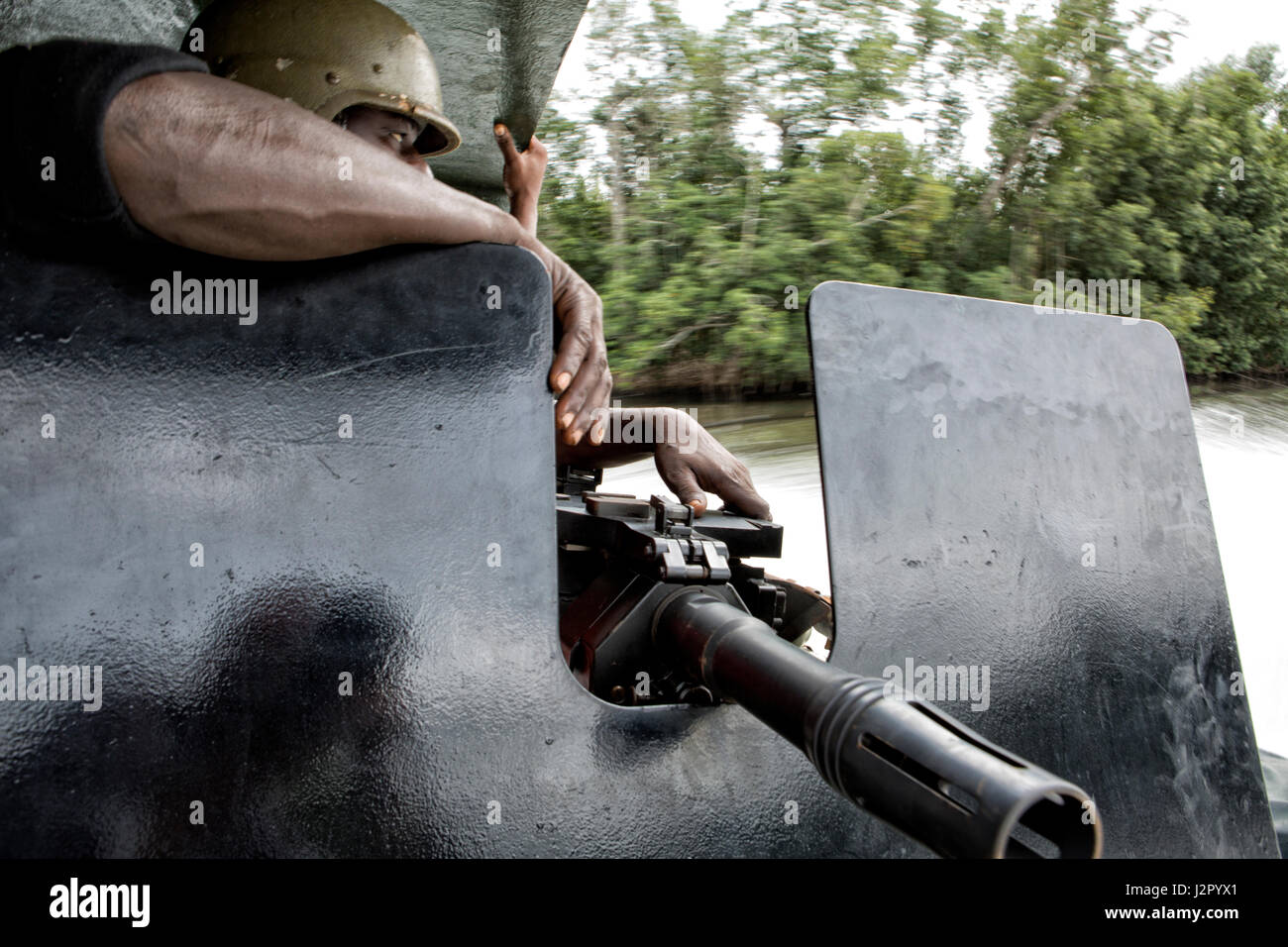 The aft gunner of a patrolboat keeps a watchfull eye during a patrol.The Nigerian Navy uses small gunboats to patrol the creeks and rivers of Delta State in their ongoing operations against millitancy and illegal oil trade, Warri Province, Delta State, Nigeria Stock Photo