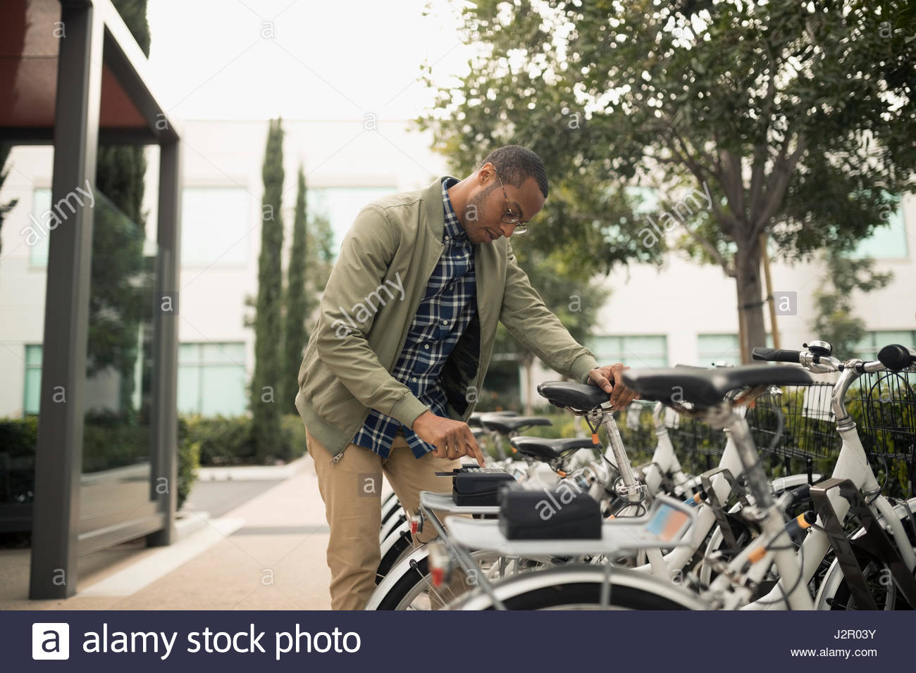 African American Businessman Using Ride Share Bicycle Outside Office 