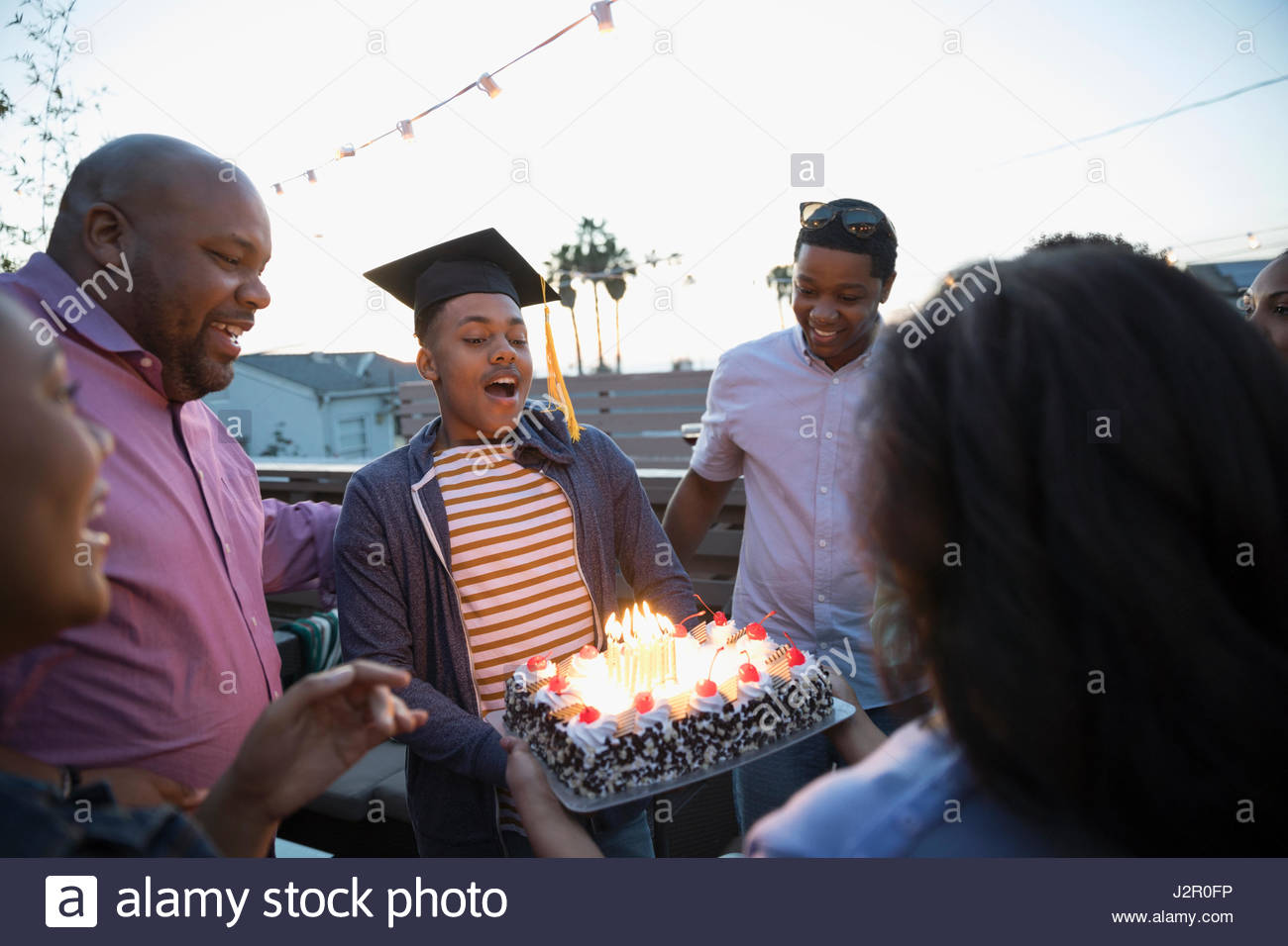 African American family celebrating graduation with cake on deck Stock Photo