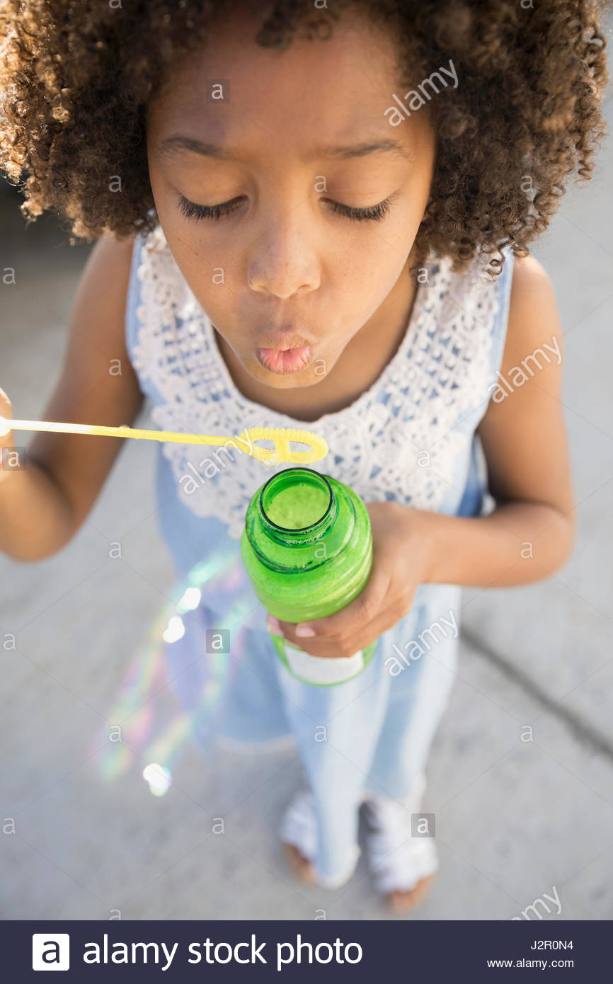 Close up African American girl blowing bubbles with bubble wand Stock
