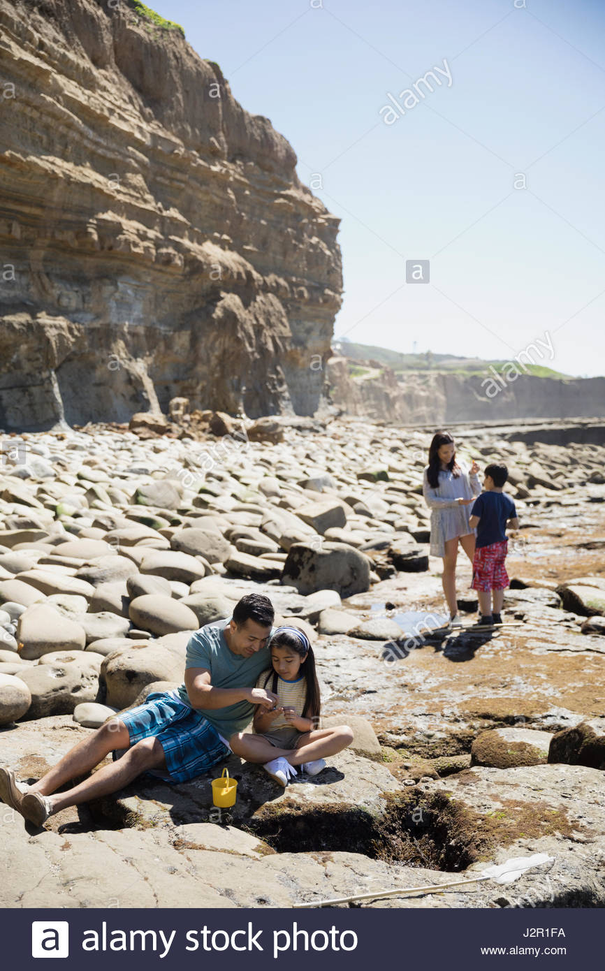 Latino family playing on sunny craggy beach Stock Photo