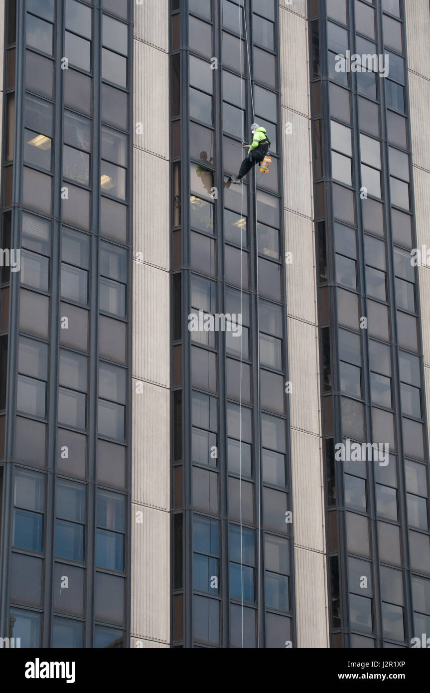 A man scales a high rise office block in Cardiff, Wales. Spraying weed killer Stock Photo