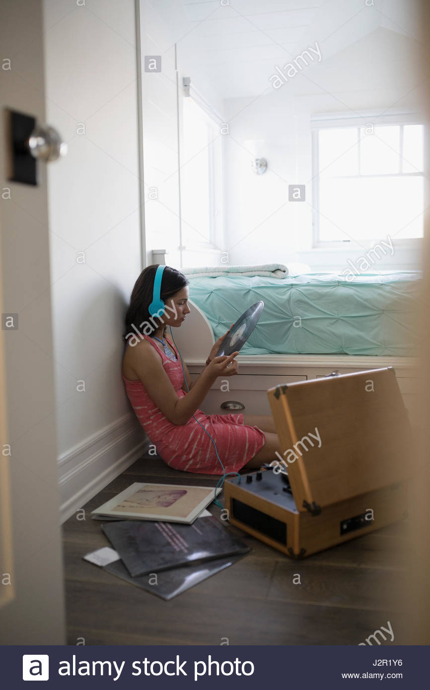 Teenage girl listening to music records with record player and