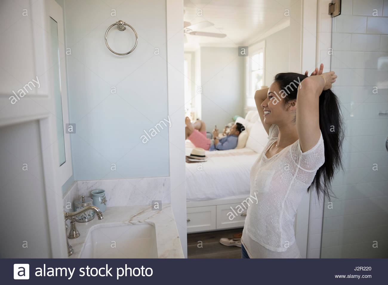Woman fixing hair into ponytail in bathroom Stock Photo