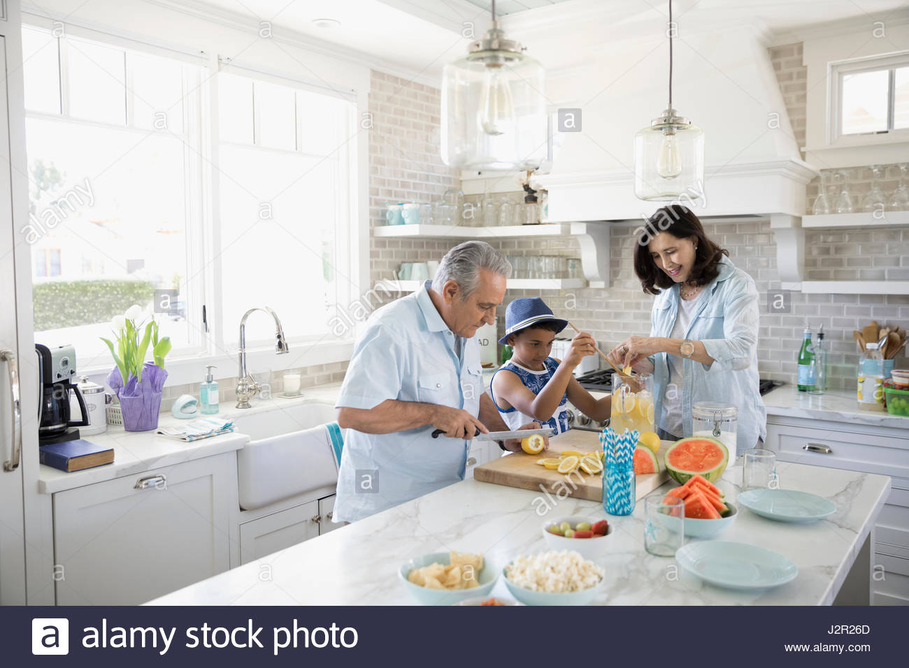Grandparents and grandson making lemonade in beach house kitchen Stock Photo