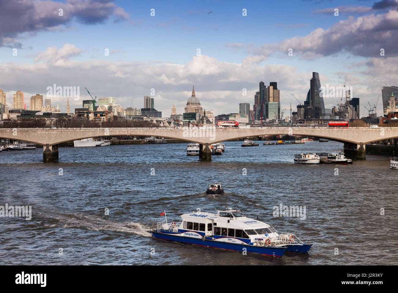 London city skyline with the River Thames and a ferry boat in the foreground Stock Photo