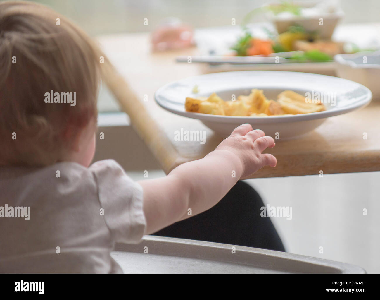 Toddler Reaching for food Hungry Hands Eating Restaurant Interior Stock Photo