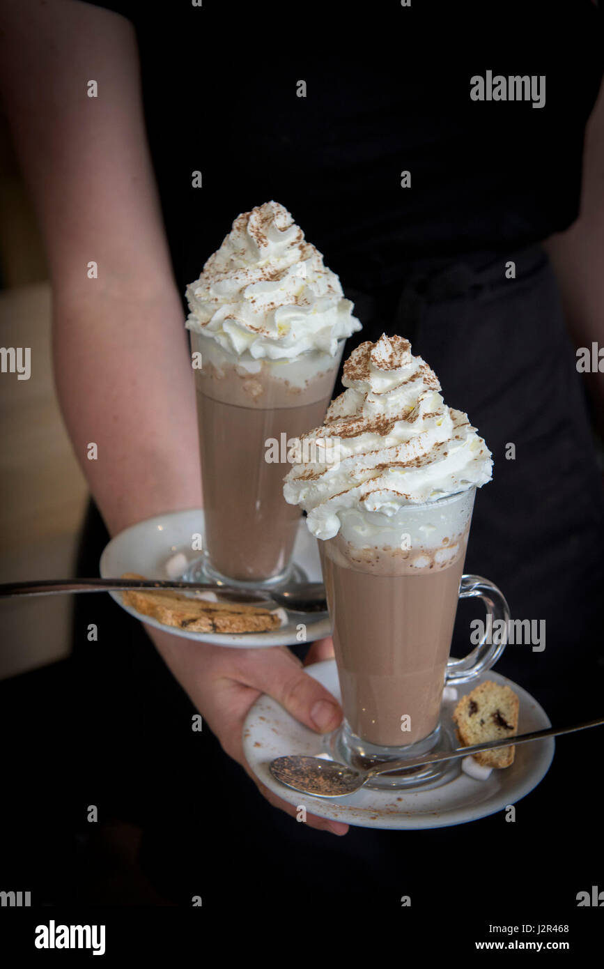 Hot chocolate with whipped cream Waitress Serving Two drinks Treat Indulgence Being served Stock Photo