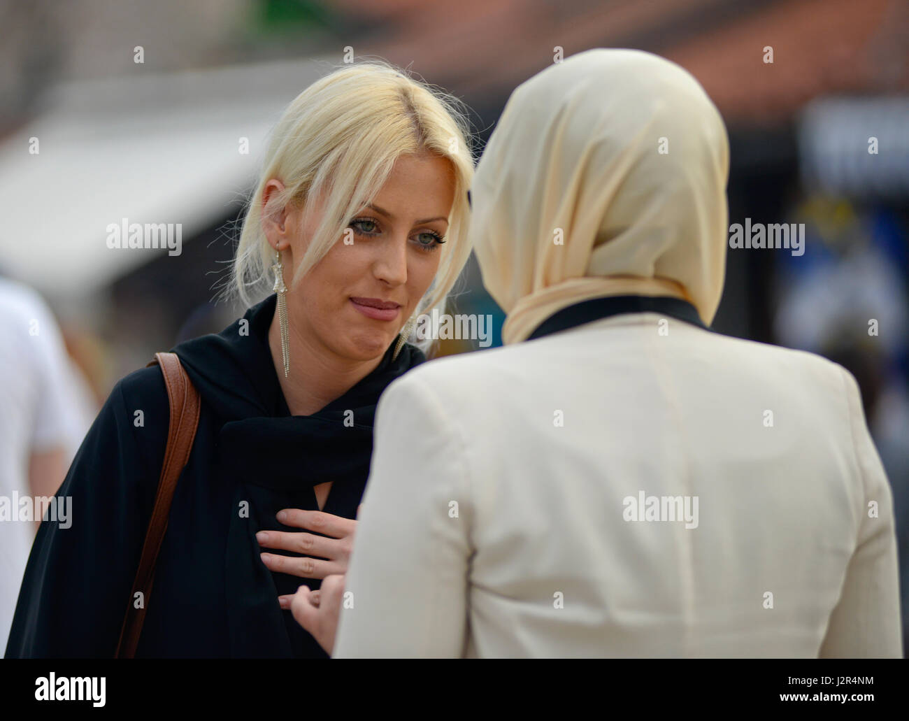 A blonde girl talks to her muslim friend Stock Photo