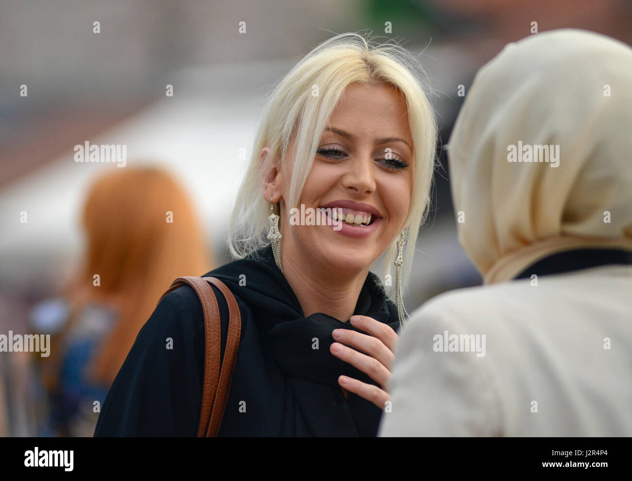 A blonde girl talks to her muslim friend Stock Photo