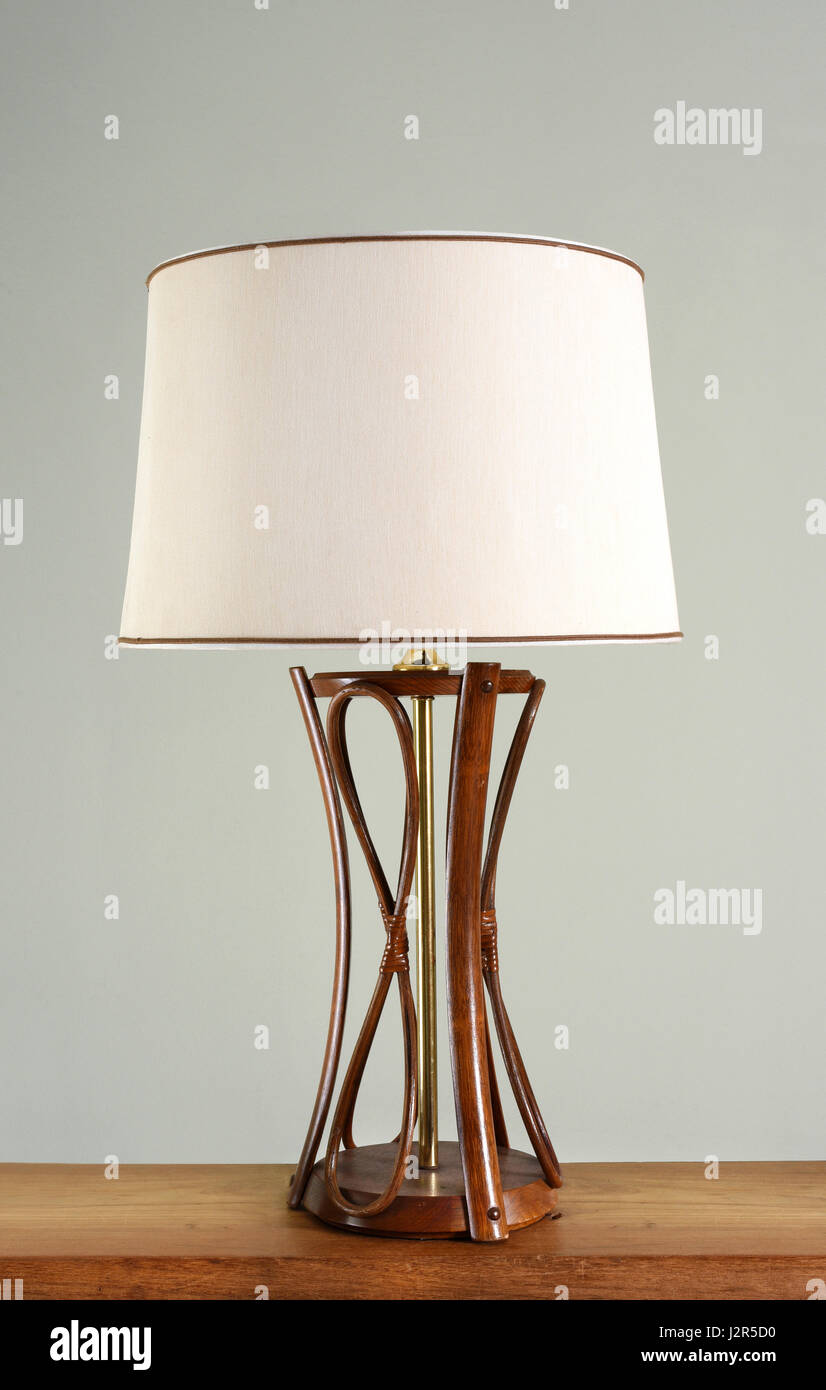 Design vintage lamp with wooden base, metal decorative leg and white fabric  shade, close-up on wooden shelf against light wall background Stock Photo -  Alamy