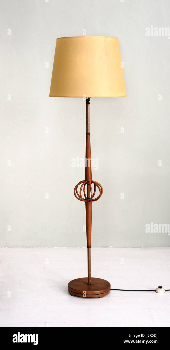 Stylish wooden electric floor lamp with yellow shade and open bentwood centrepiece in an interior decor concept Stock Photo