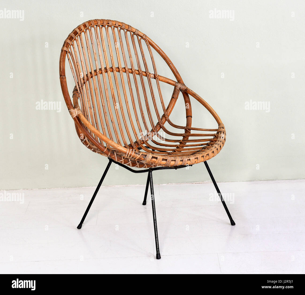Comfortable round wicker chair with metal legs made with intertwined willow canes in an interior decor and design concept Stock Photo
